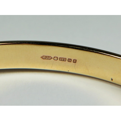 526 - 9ct Yellow Gold Hinged bangle with scrolled decoration to one side. Safety chain fitted. Good order.... 