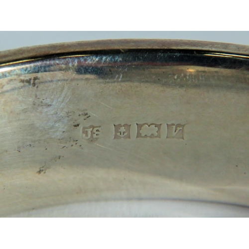 536 - 925 Hallmarked sterling silver bangle. Inscribed flowers to both sides. Safety chain fitted to nip u... 