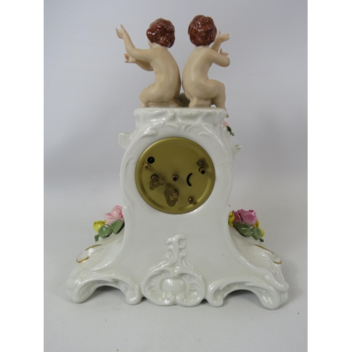 738 - Dresden porcelain clock decorated with 2 cherubs. 25cm tall and clock in running order. ( 1 cherub h... 