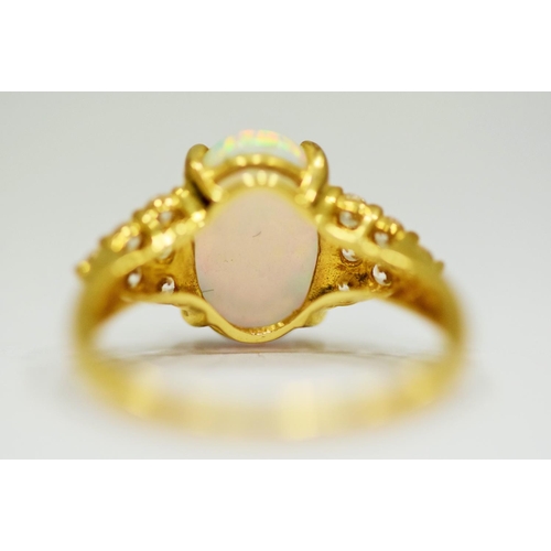 314 - 14ct Yellow Gold Ring set with a large central Opal which measures 12 x 8mm with 12 clear gemstones ... 