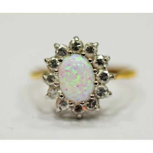 327 - 9ct Yellow Gold ring set with a lovely Central Opal which measures 8 x 5mm, surrounded by Clear gems... 