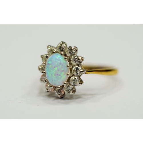 327 - 9ct Yellow Gold ring set with a lovely Central Opal which measures 8 x 5mm, surrounded by Clear gems... 