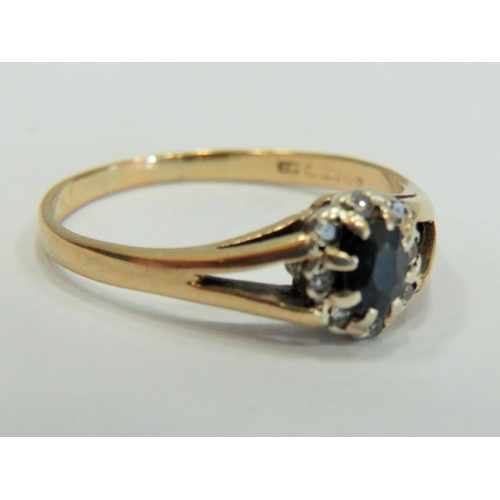 356 - 9ct Yellow Gold ring set with a central Sapphire with large claw mounts and surrounded by small Mele... 