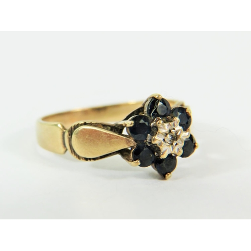 132 - 9ct Yellow Gold ring set with a small Central Diamond and surrounded by  six small Sapphires. .. Fin... 