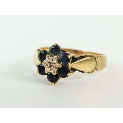 132 - 9ct Yellow Gold ring set with a small Central Diamond and surrounded by  six small Sapphires. .. Fin... 