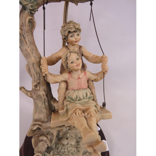 500 - B Merli Italian figural lamp of children on a swing, 21 