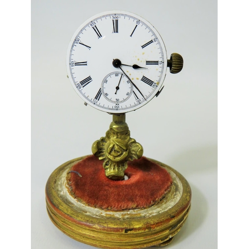 60 - Unusual enamel faced Pocket watch which has been mounted on a brass and wooden stand and under a gla... 