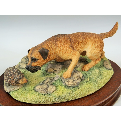 81 - Border Fine arts model of a Border Terrier with a Hedgehog. Mounted on wooden base it measures appro... 