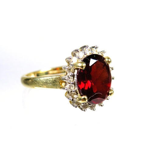 445 - 9ct Yellow Gold ring set with a large Oval Garnet which measures approx 10 x 8 mm with Diamond Surro... 