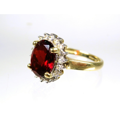 445 - 9ct Yellow Gold ring set with a large Oval Garnet which measures approx 10 x 8 mm with Diamond Surro... 