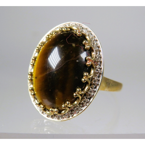 448 - 9ct Yellow Gold ring set with a large 'Tiger's Eye' stone which measures approx 20 x 14 mm with smal... 