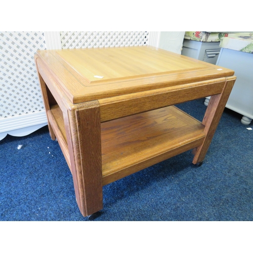 389 - Oak and Light wood occasional table with shelf under. Mounted on castors it measures approx 21 x 26 ... 