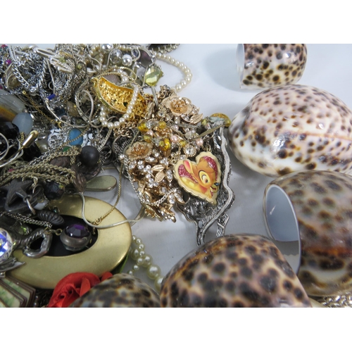 573 - Over 3.5kgs of costume jewellery and a set of cowrie shell napkin rings.