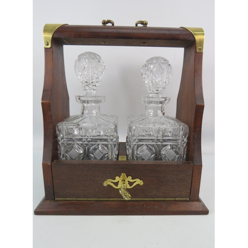 719 - Oak two decanter Tantalus with brass fittings and 2 cut glass decanters.