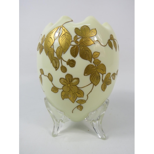 51 - An Opaline uranium glass egg shaped vase with ruffled rim and gilded decoration standing on three cl... 