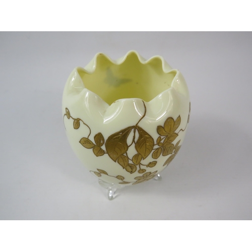 51 - An Opaline uranium glass egg shaped vase with ruffled rim and gilded decoration standing on three cl... 