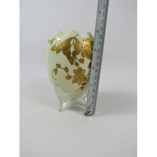 51 - An Opaline uranium glass egg shaped vase with ruffled rim and gilded decoration standing on three cl... 