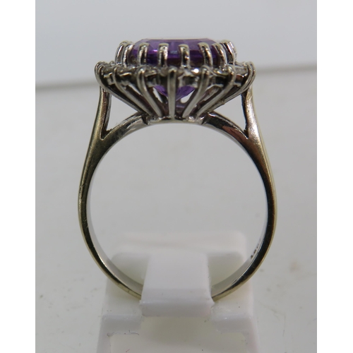 325 - 18ct White gold ring set with a large central Amethyst (12mm by 10mm) and surrounded by diamonds, fi... 