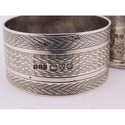121 - Two sterling silver napkin rings, comprising a Birmingham example dated 1928 with engine-turned deco... 
