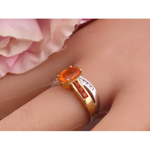 129 - A 9ct yellow and white gold ring set with an oval fire opal accented by small brilliant cut diamonds... 