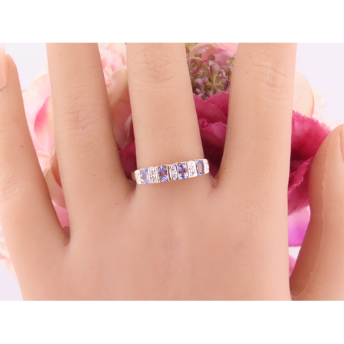 130 - A 14ct yellow gold ring set with rectangular cut tanzanites interspersed with small diamonds in a ch... 