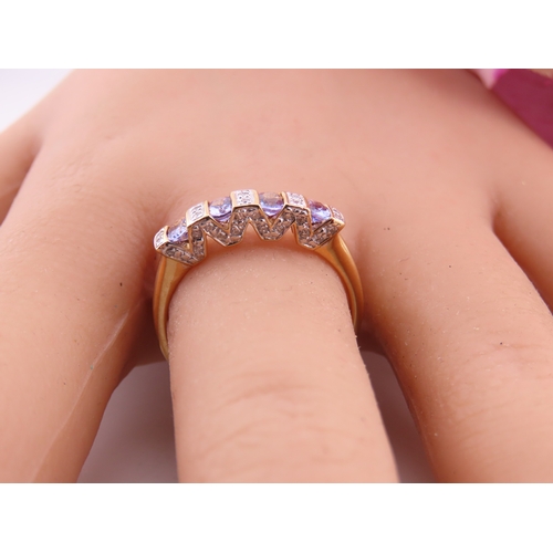130 - A 14ct yellow gold ring set with rectangular cut tanzanites interspersed with small diamonds in a ch... 