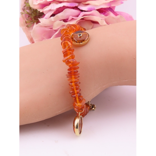 183 - 9ct Gold Amber Bracelet. Composed of graduated amber beads with applied 9ct gold mounts charms and c... 