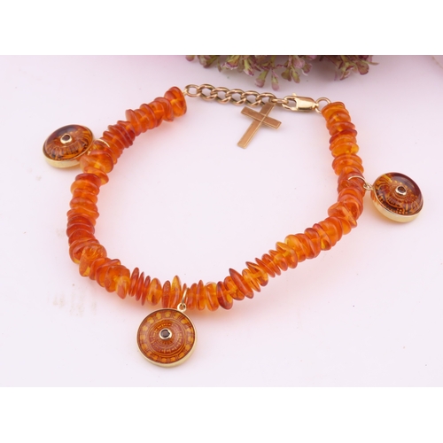 183 - 9ct Gold Amber Bracelet. Composed of graduated amber beads with applied 9ct gold mounts charms and c... 