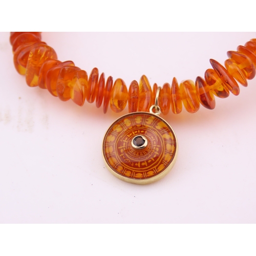 183 - 9ct Gold Amber Bracelet. Composed of graduated amber beads with applied 9ct gold mounts charms and c... 