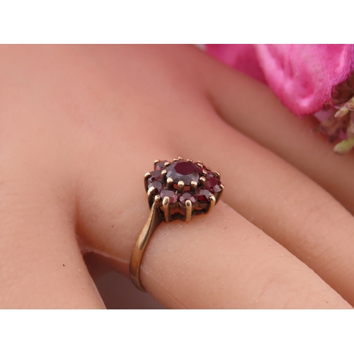 191 - A 9 carat gold garnet cluster ring, the central garnet surrounded by a halo of matching garnets in a... 