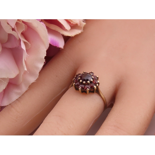 191 - A 9 carat gold garnet cluster ring, the central garnet surrounded by a halo of matching garnets in a... 