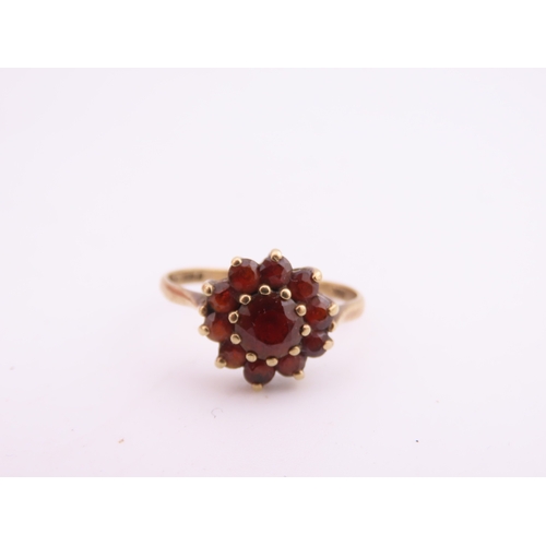 191 - A 9 carat gold garnet cluster ring, the central garnet surrounded by a halo of matching garnets in a... 