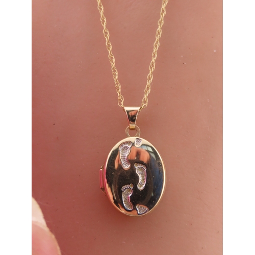 192 - A 9 carat gold oval locket, the front decorated with a raised footsteps motif, opening to reveal a g... 