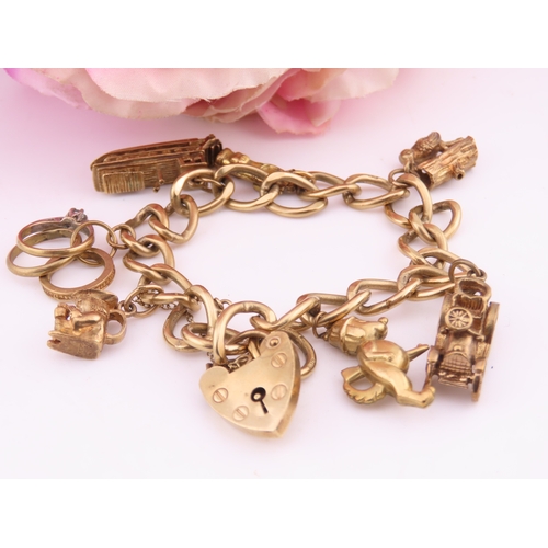 195 - A 9 carat gold charm bracelet, composed of a curb link chain fitted with a padlock clasp and suspend... 