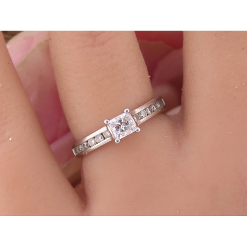 196 - A platinum diamond ring, set with a square cut central diamond flanked by graduated diamonds to each... 