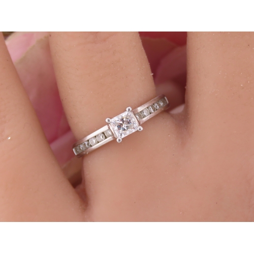 196 - A platinum diamond ring, set with a square cut central diamond flanked by graduated diamonds to each... 