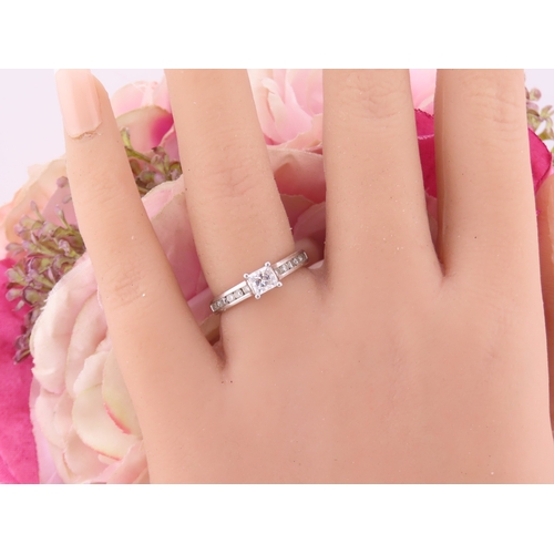 196 - A platinum diamond ring, set with a square cut central diamond flanked by graduated diamonds to each... 