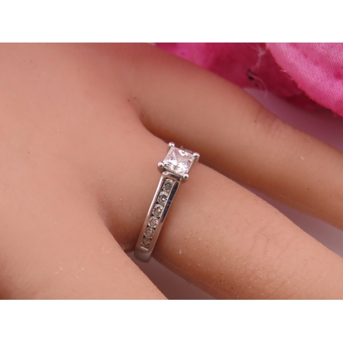 196 - A platinum diamond ring, set with a square cut central diamond flanked by graduated diamonds to each... 