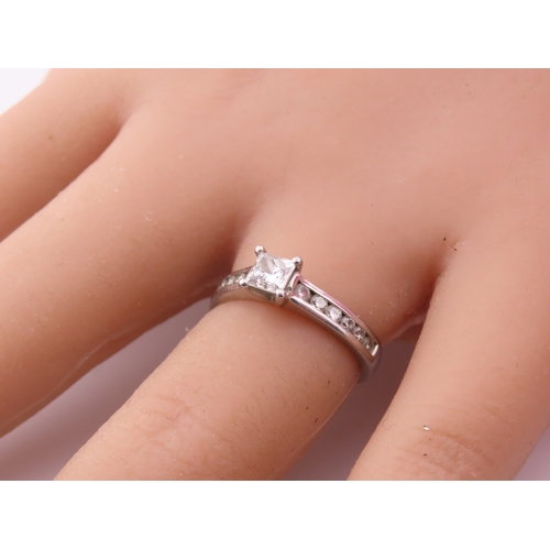 196 - A platinum diamond ring, set with a square cut central diamond flanked by graduated diamonds to each... 