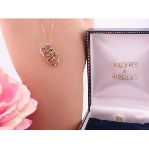 197 - A Brooks Bentley 9 carat tri colour gold heart pendant, formed as an interlocking three heart design... 
