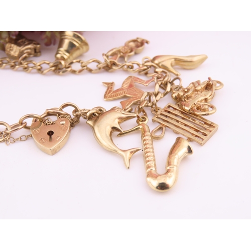 198 - A 9 carat gold charm bracelet, fitted with a padlock clasp and suspending seventeen assorted gold ch... 
