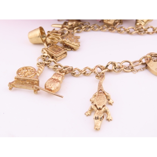 198 - A 9 carat gold charm bracelet, fitted with a padlock clasp and suspending seventeen assorted gold ch... 