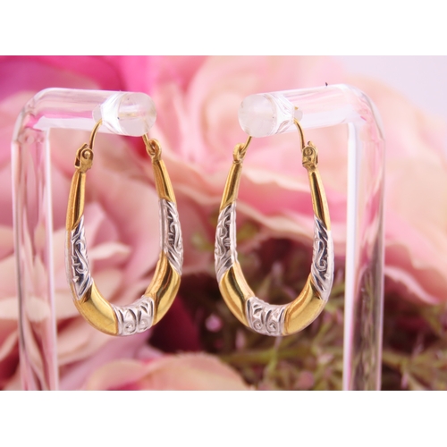 200 - A pair of 9 carat yellow and white gold hoop earrings, of oval form with engraved white gold detaili... 