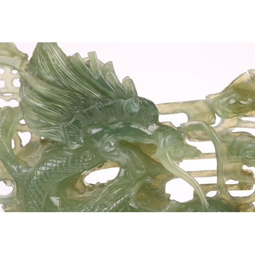 1235 - A contemporary Chinese variegated celadon jade carved and pierced study of two writhing dragons cont... 