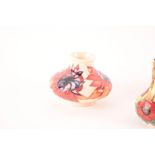 76 - A collection of Moorcroft vases comprising short vase with red and magenta decoration on white groun... 