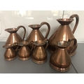 Seven graduated copper jugs gallon to 1/2 gill.