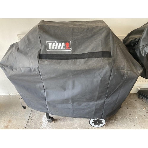 1439 - A Weber Spirit barbeque with protective cover.