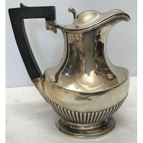 493 - An Edwardian hallmarked silver hot water jug, baluster form with half gadrooning on a raised oval fo... 