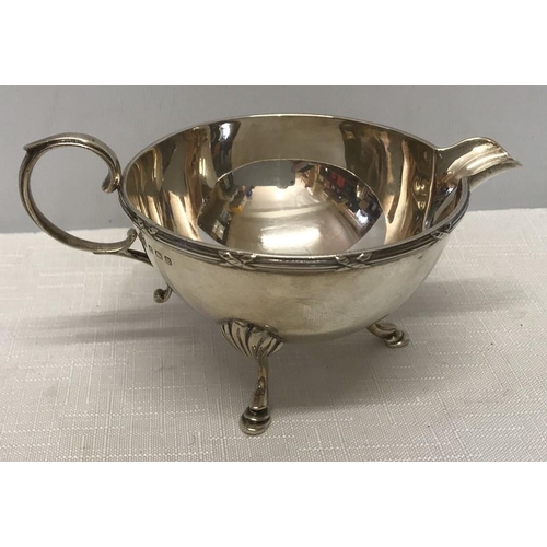 496 - Hallmarked silver sauce jug on three feet. George Unite, Birmingham 1926. 131gms. 7cms h.