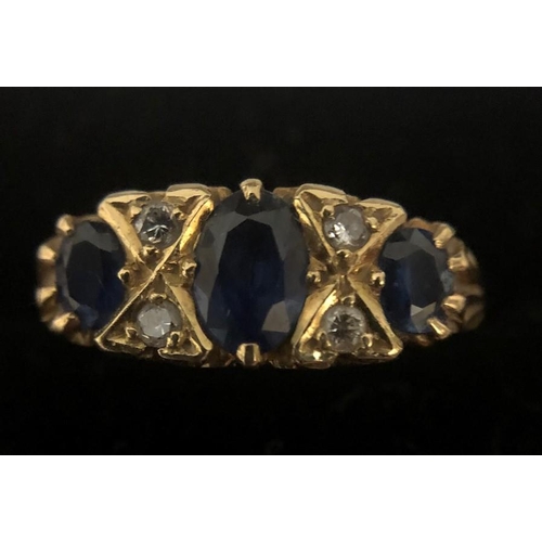 569 - A 3 stone sapphire and diamond ring in 18ct yellow gold, size N. 3.1gms.